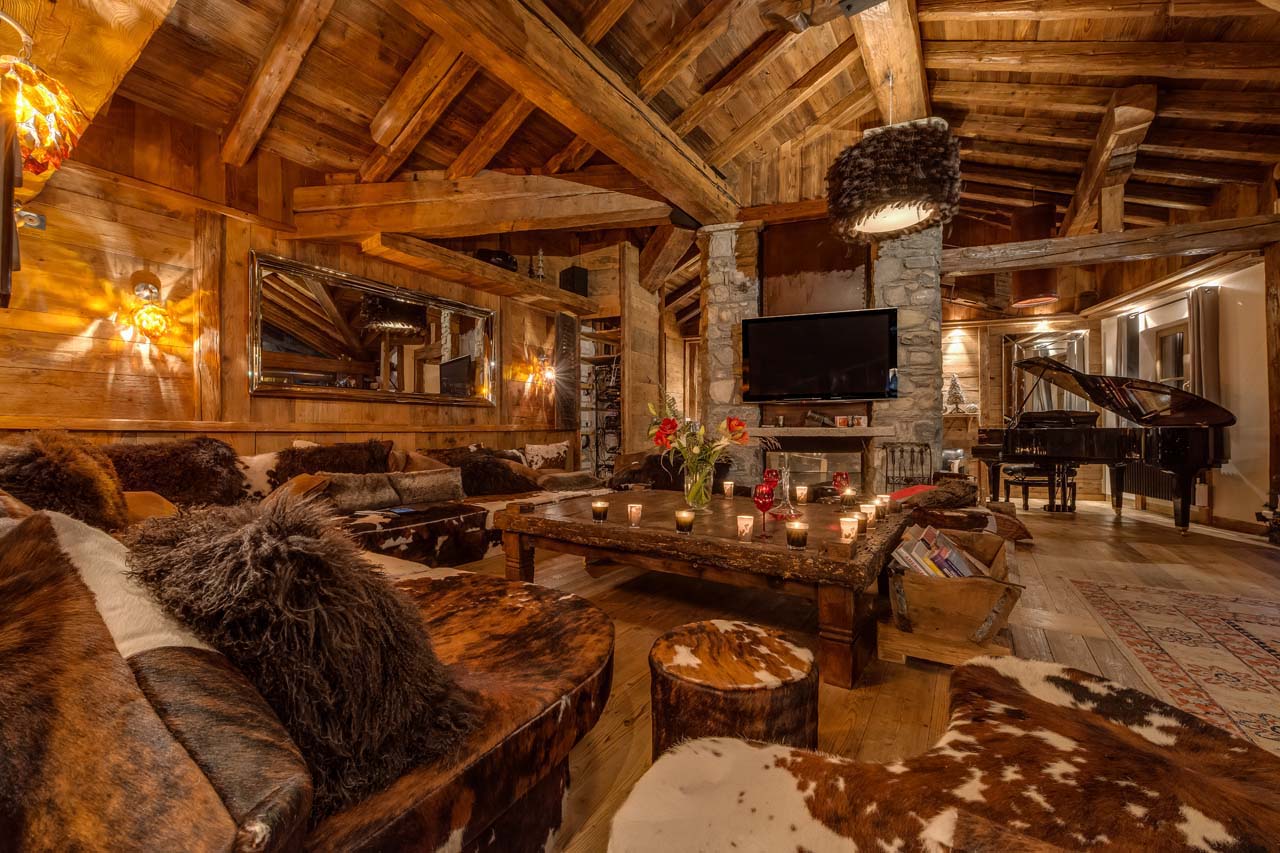 Semi-open living area with comfortable sofas and a grand piano in Chalet Lhotse in Val d’ Isere
