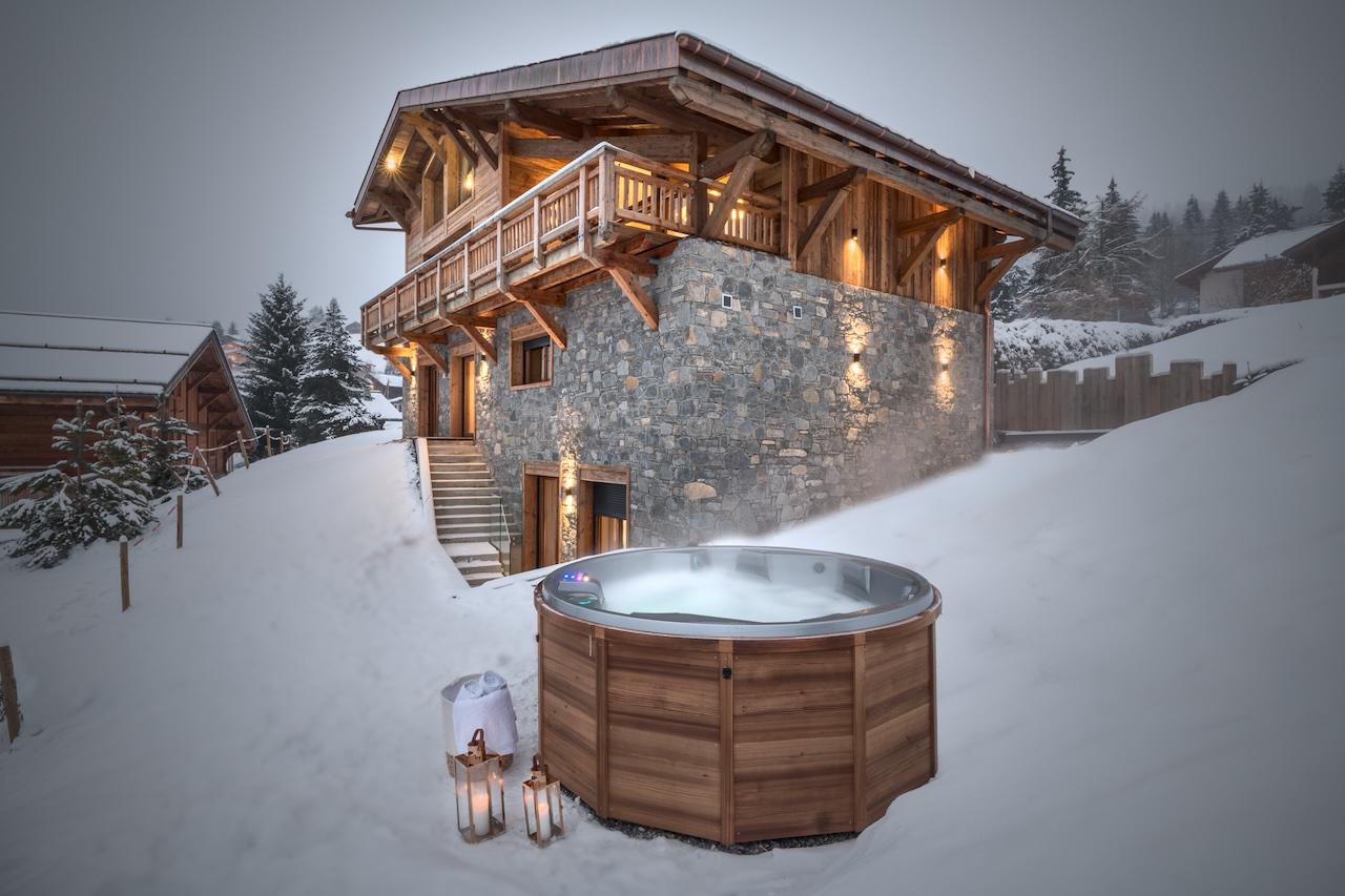 Snowy chalet exterior with outdoor hot tub at Chalet Tosca in Les Gets