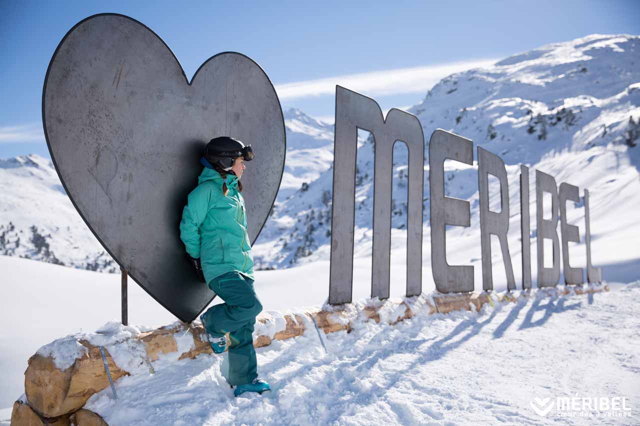 Girl leaning on Meribel sign in the snow