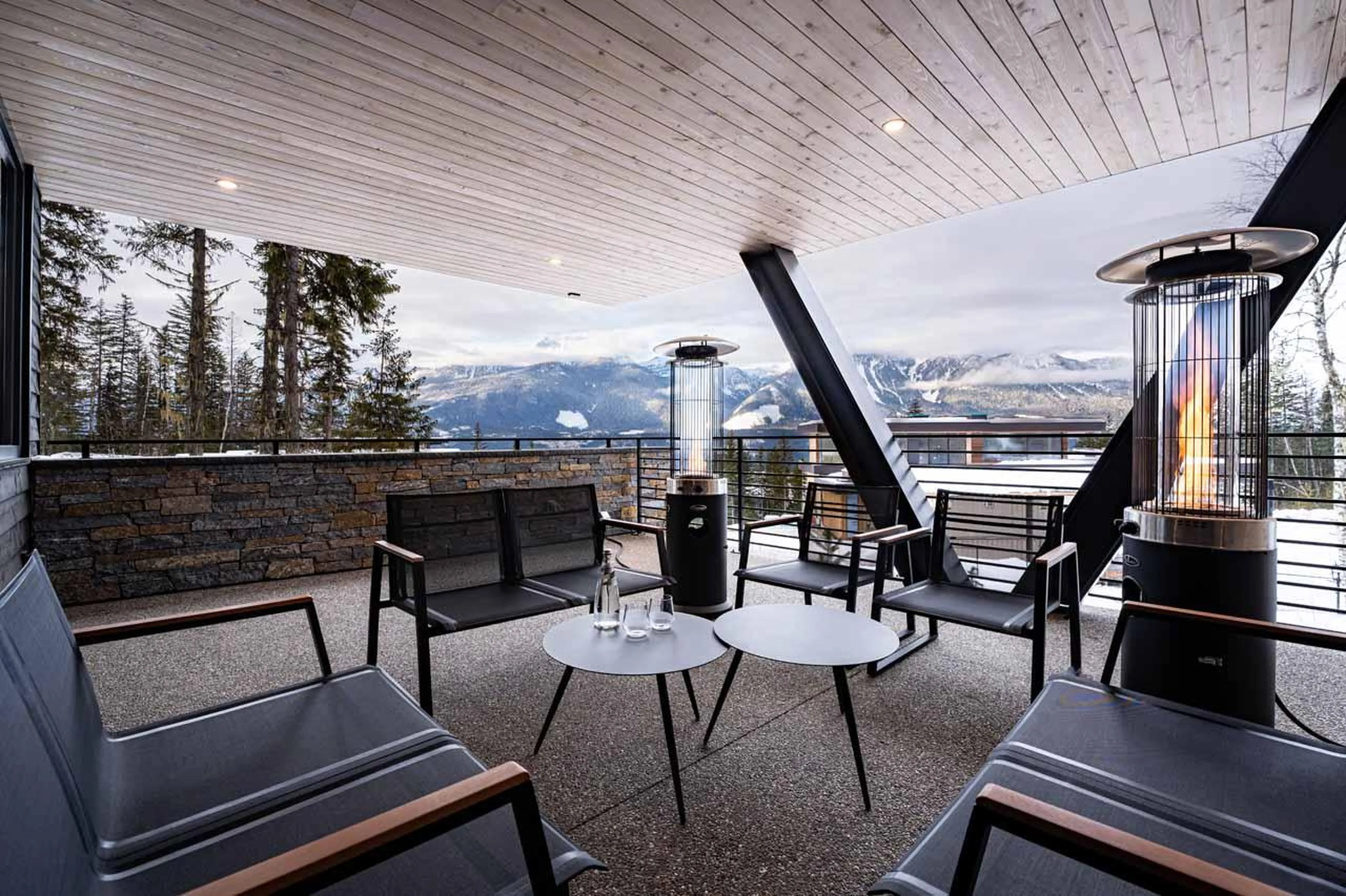 Covered front patio area with seating and heat towers at Arrowhead Lodge in Revelstoke