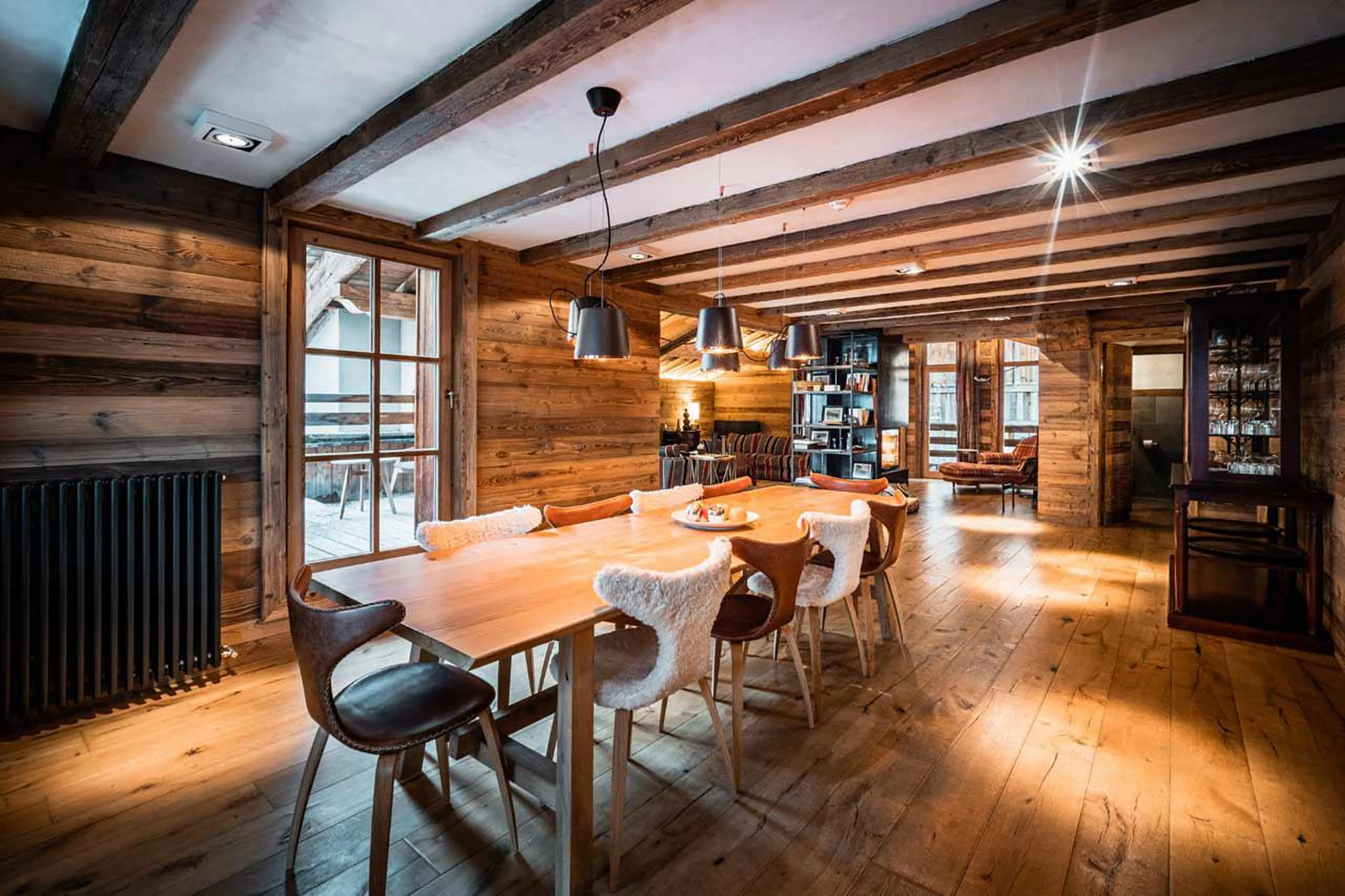 Well-lit dining area with access to the large balcony of Chalet Ambre in Val d’ Isere
