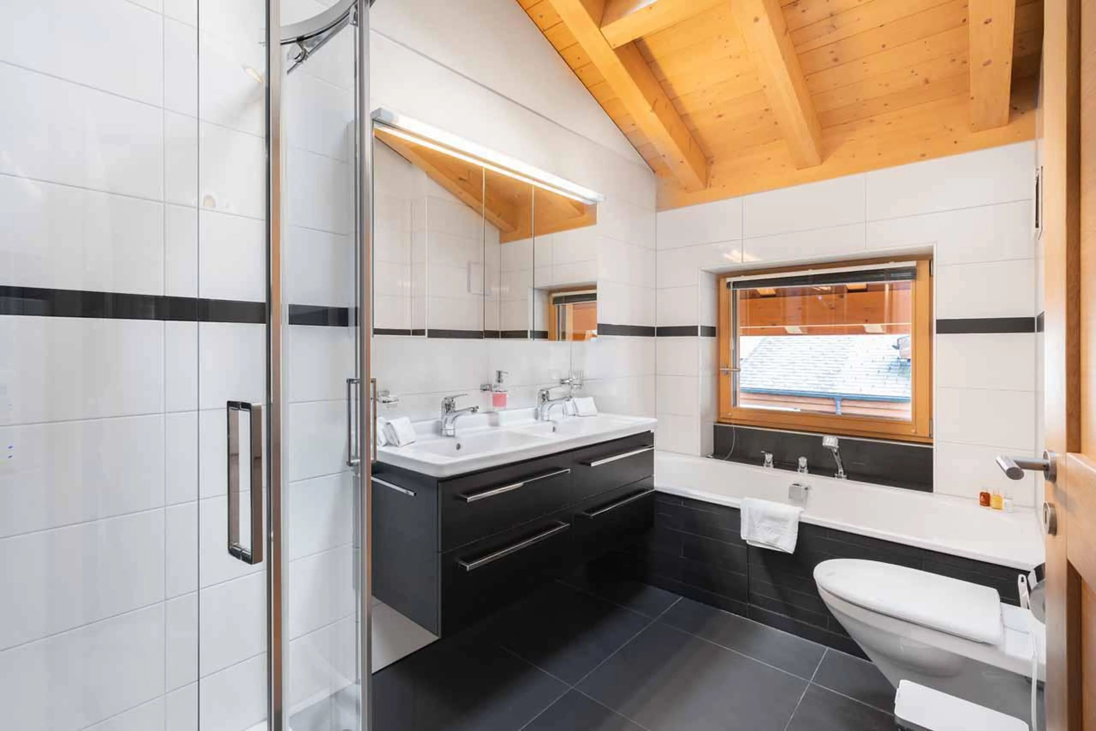 En-suite bathroom with bath and shower at Apartment Antara in Grindelwald