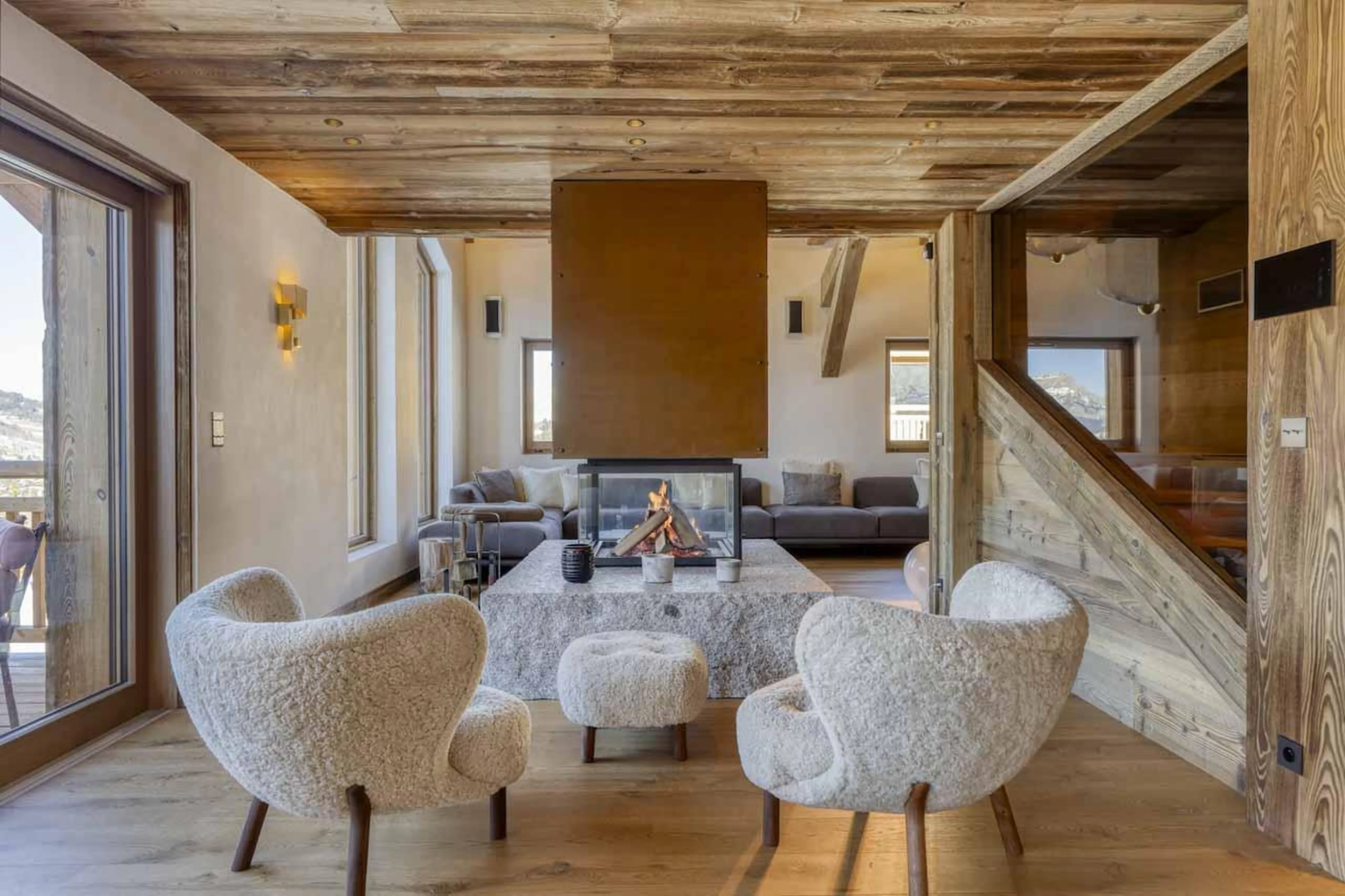 Two chairs in front of central fireplace in Chalet Aspen, Megeve