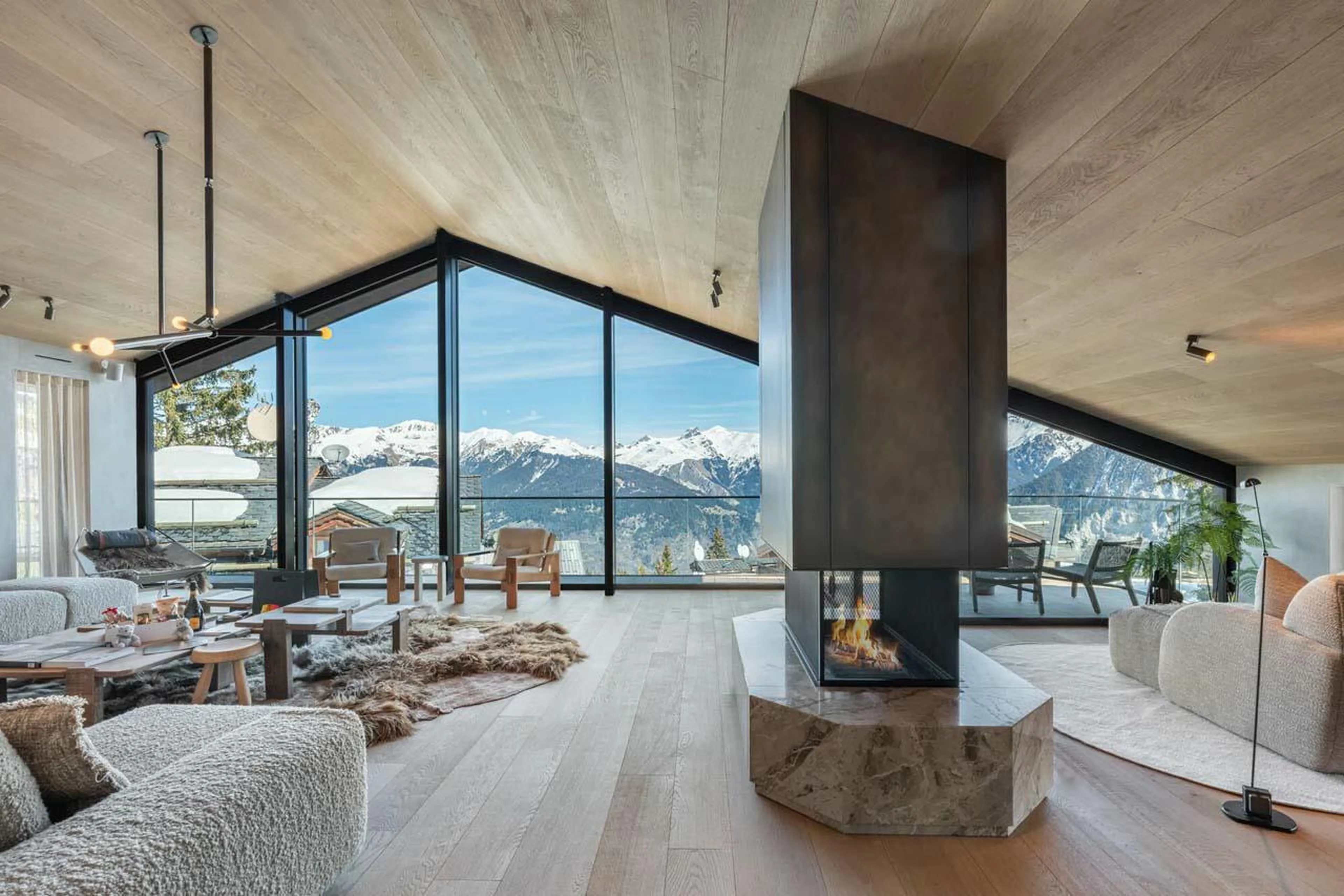 Central fireplace and floor-to-ceiling windows at Chalet Black Lodge in Courchevel 1850