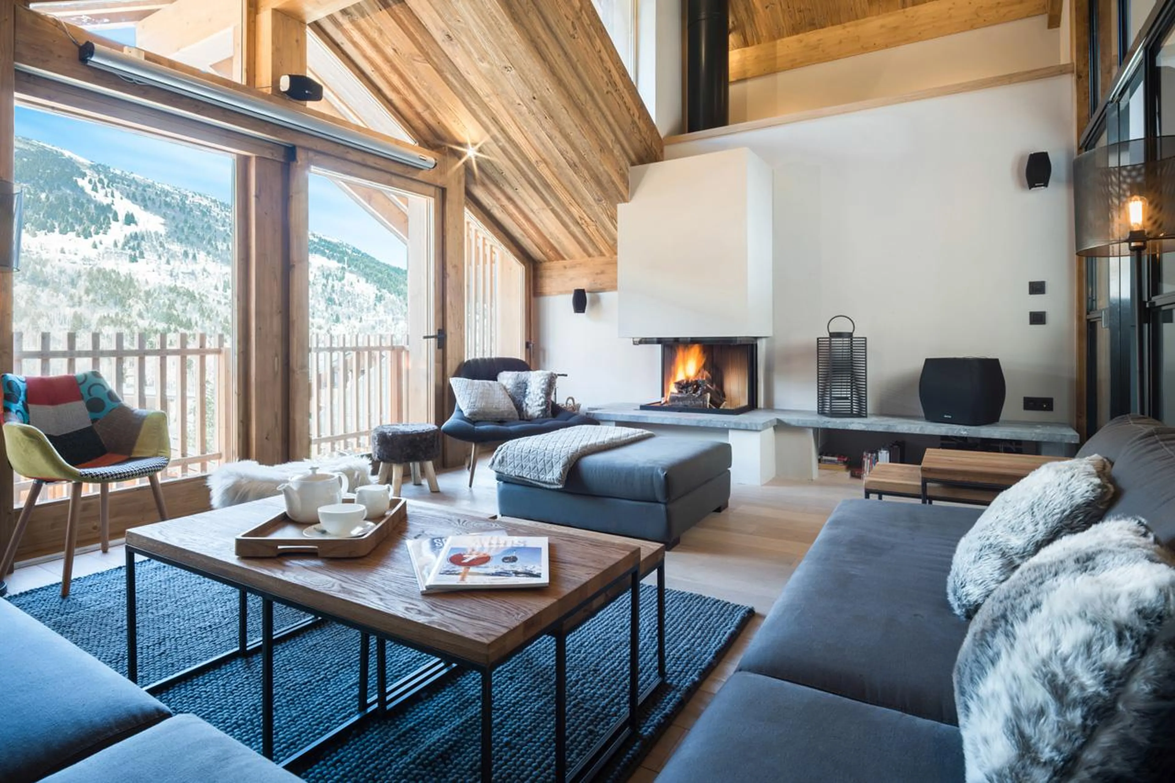 Living area with sofas, fireplace and floor-to-ceiling windows and doors in Chalet Caro, Meribel