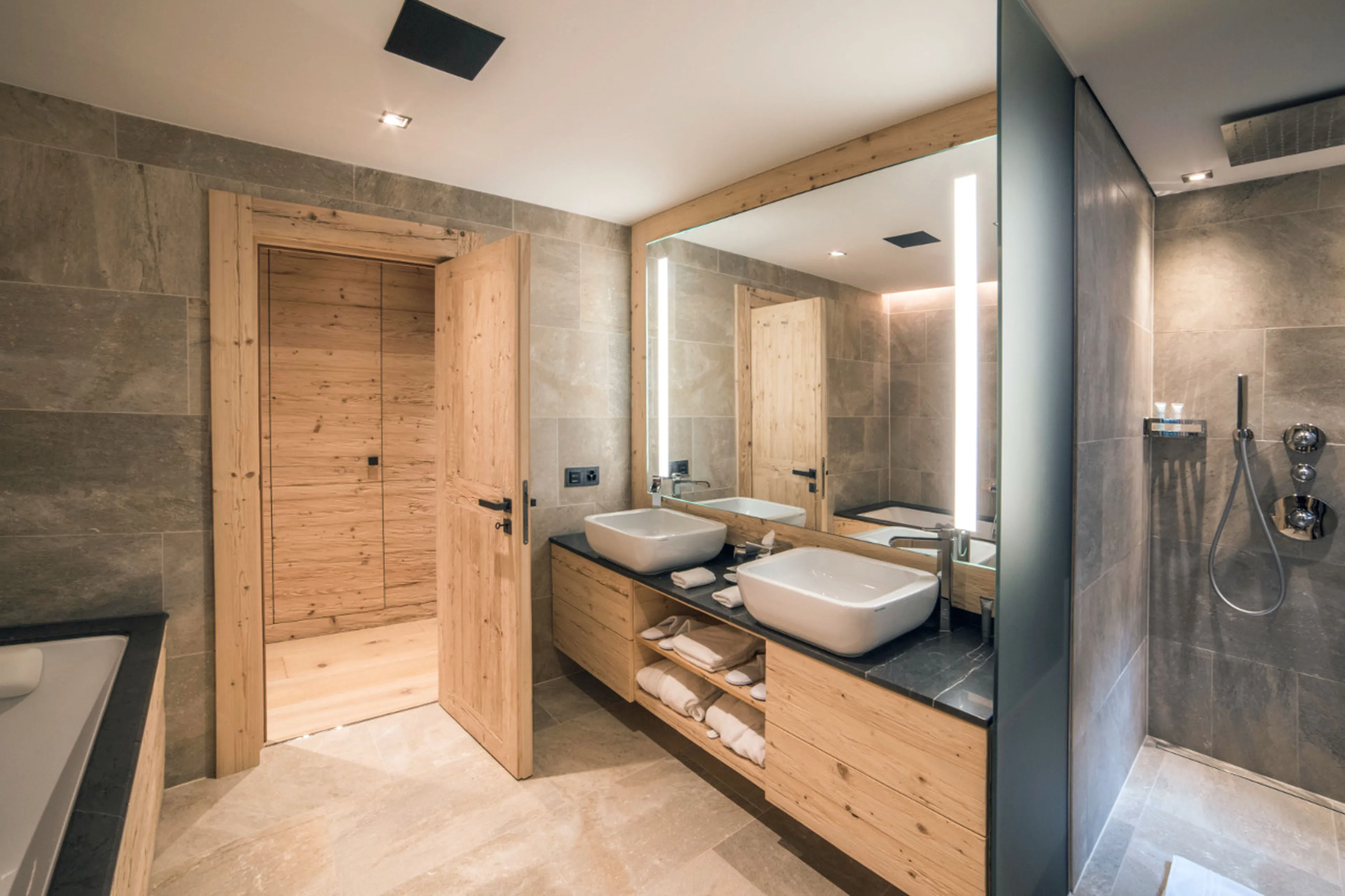 En-suite bathroom with bath and shower in Chalet de Rougemont in Gstaad