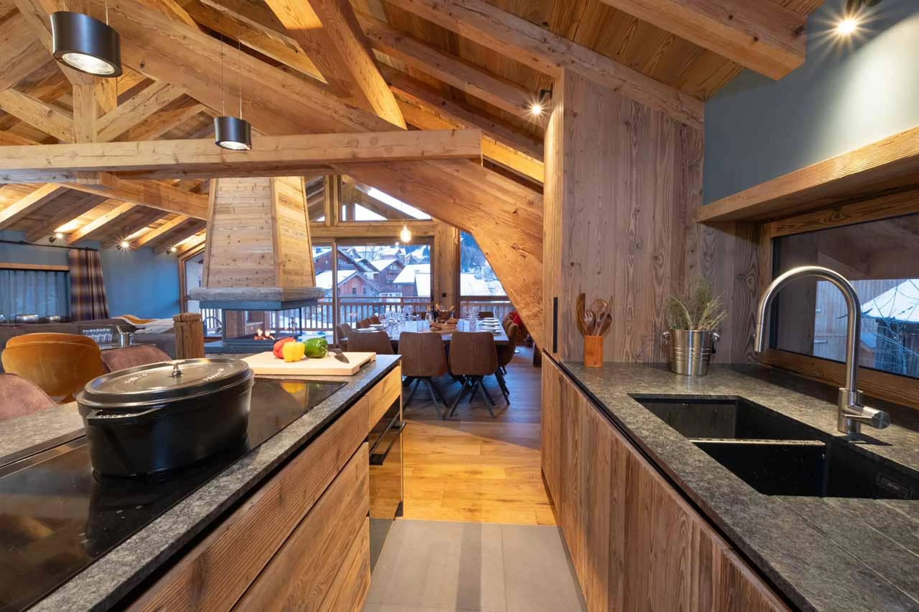 Kitchen flowing into sitting area with fireplace in Chalet Kalinka, Meribel