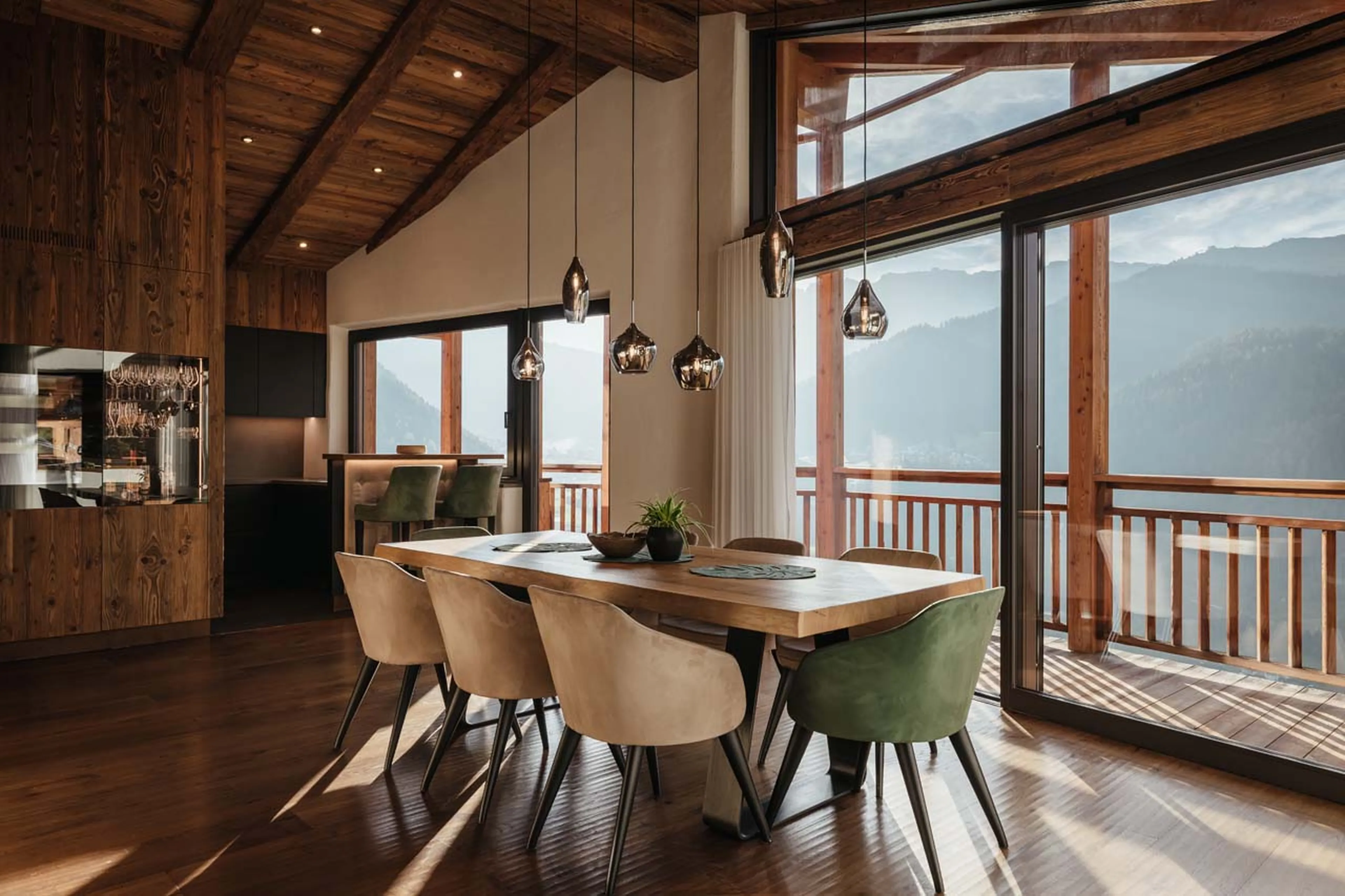 Dining table beneath expansive glass windows in Chalet Lefiro, Val Gardena