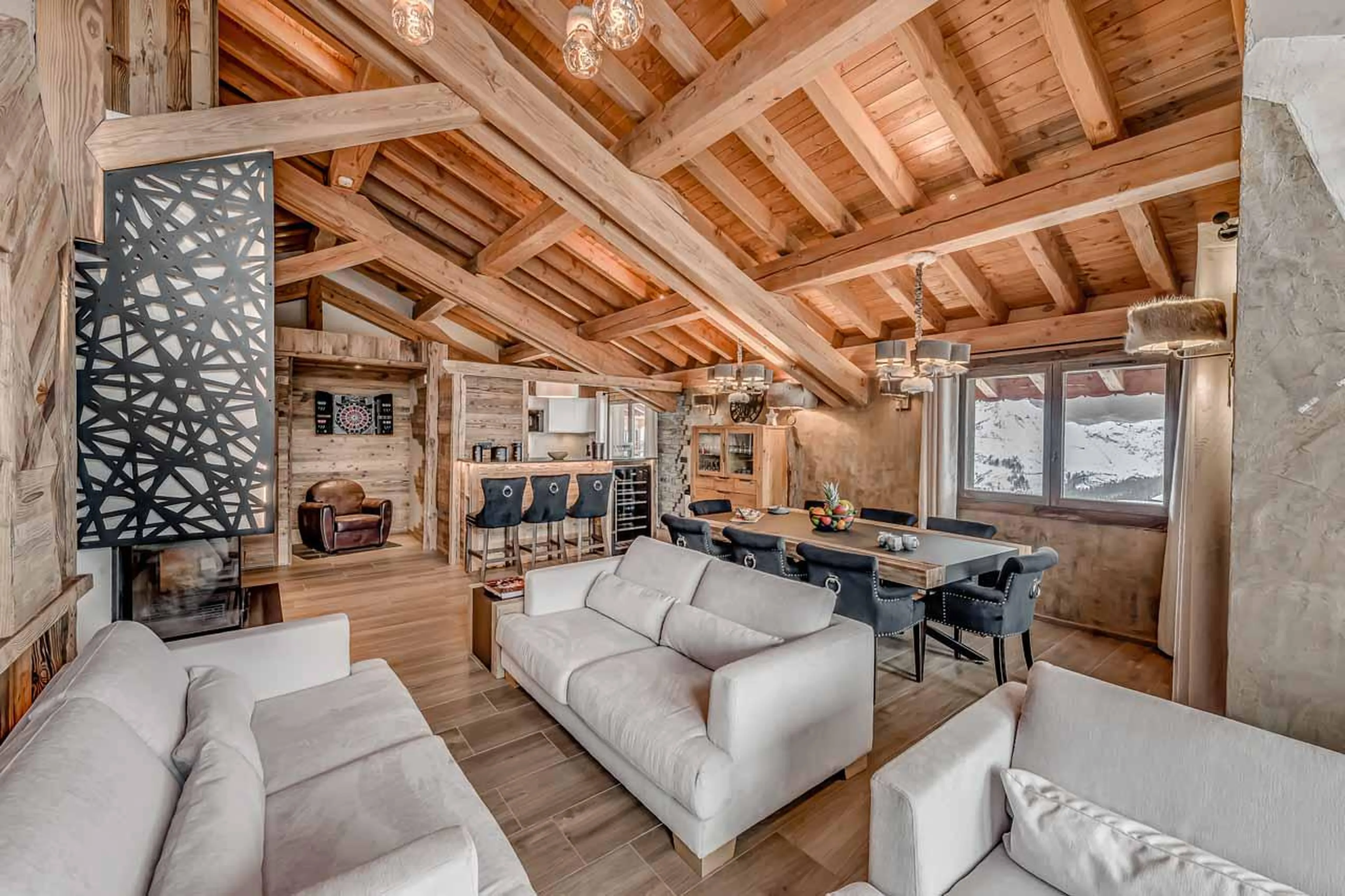 Sociable open living space with sofas, dining table and bar at Chalet Macha in Tignes