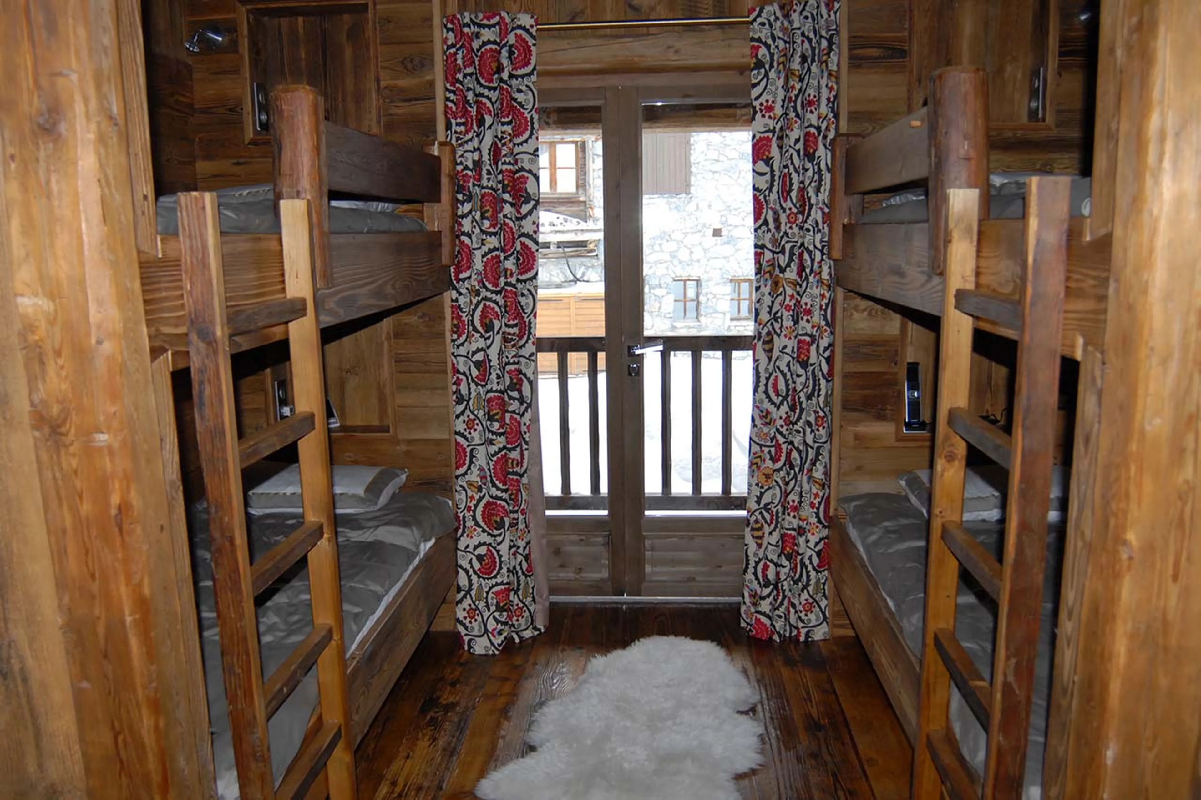 Bedroom with two bunk beds, en suite shower room and private balcony access in Chalet Marco polo in