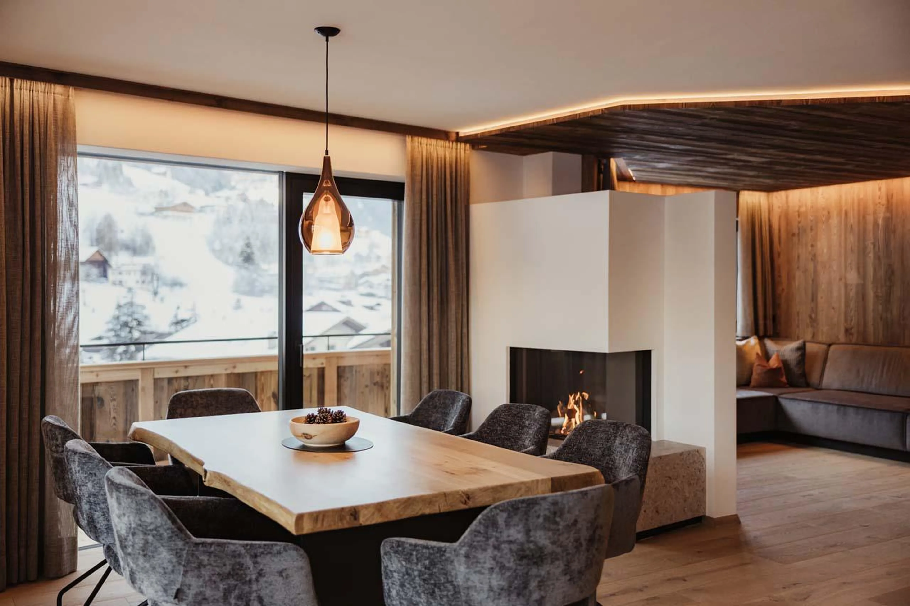 Dining table, gas fireplace and expansive floor-to-ceiling windows at Chalet Mile 2 in Val Gardena