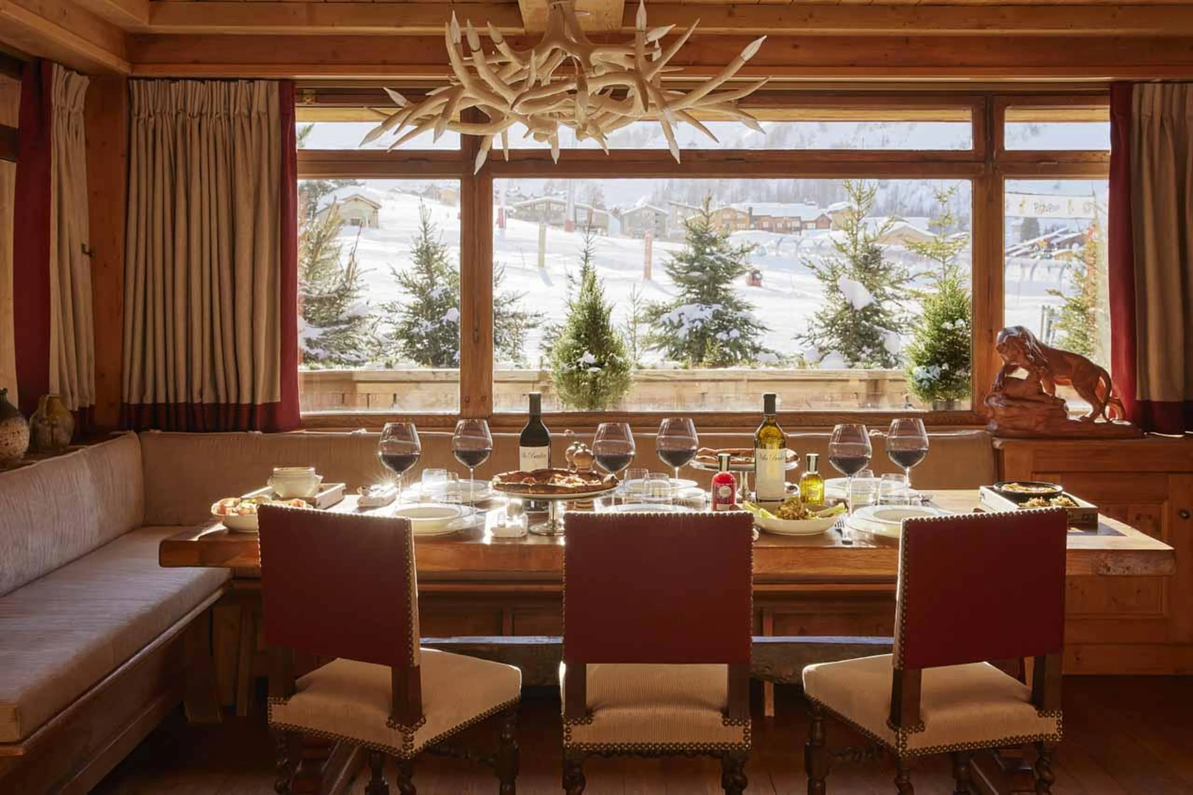 Dining table beneath window looking out to the piste in Chalet Schuss, Val d'Isere