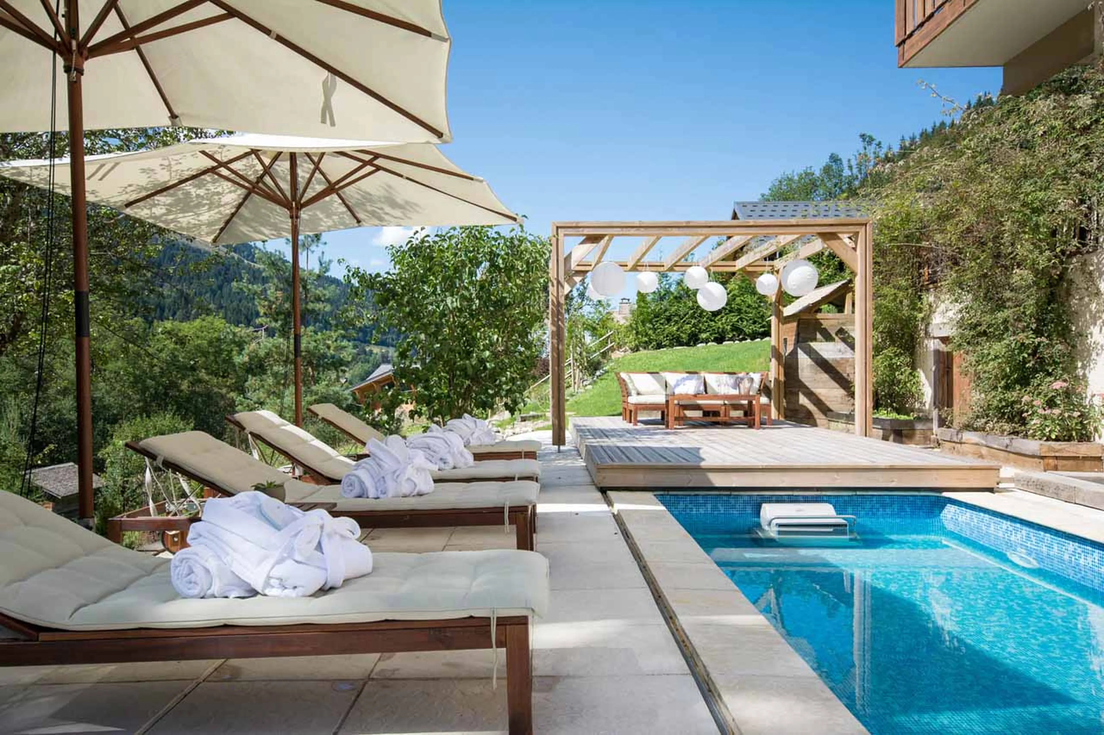 Sun loungers beside pool at  Chalet Twenty 26 in Morzine