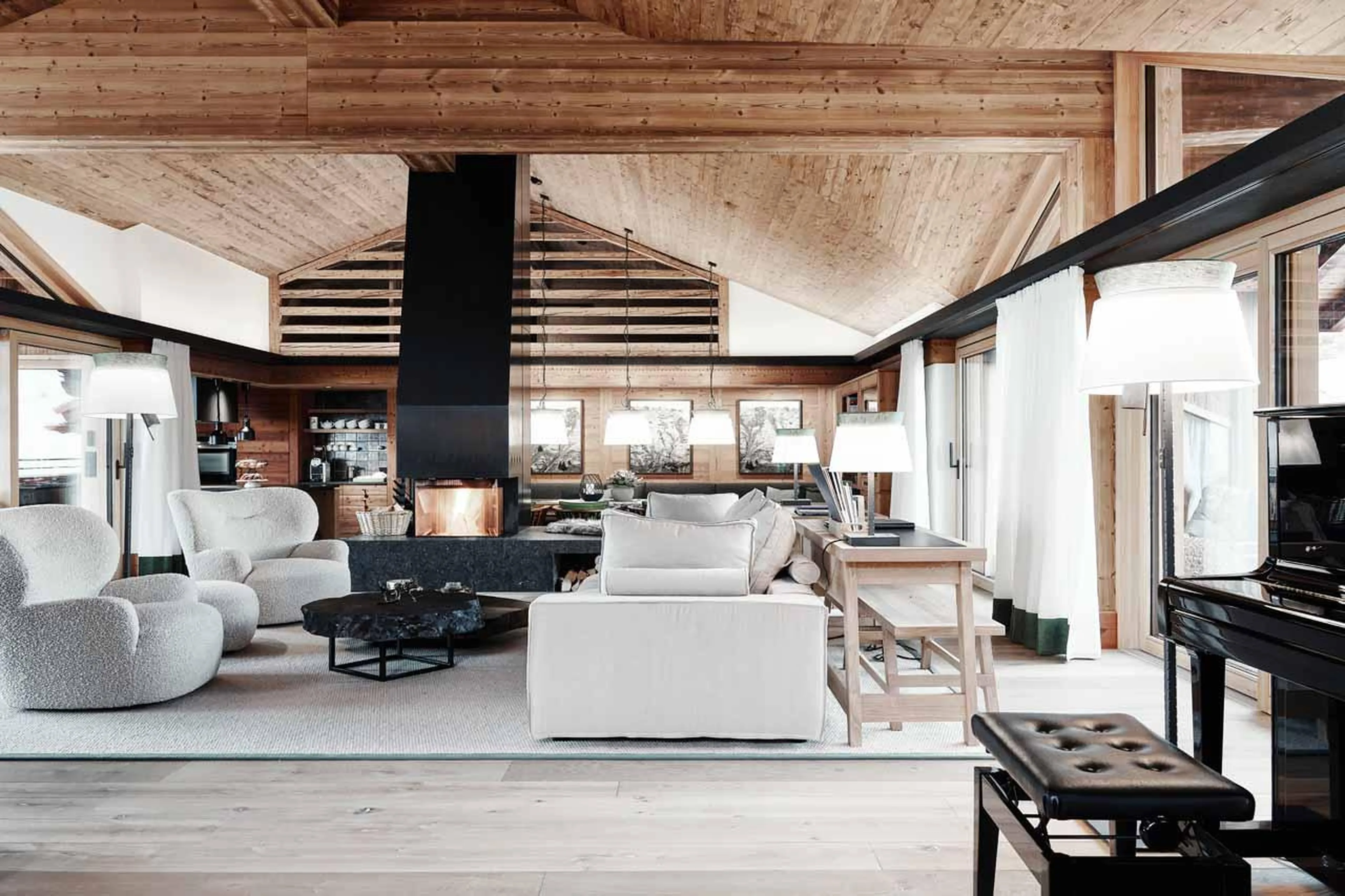 Comfortable sofas and armchairs surrounding central fireplace in Lech Lodge Loft, Lech