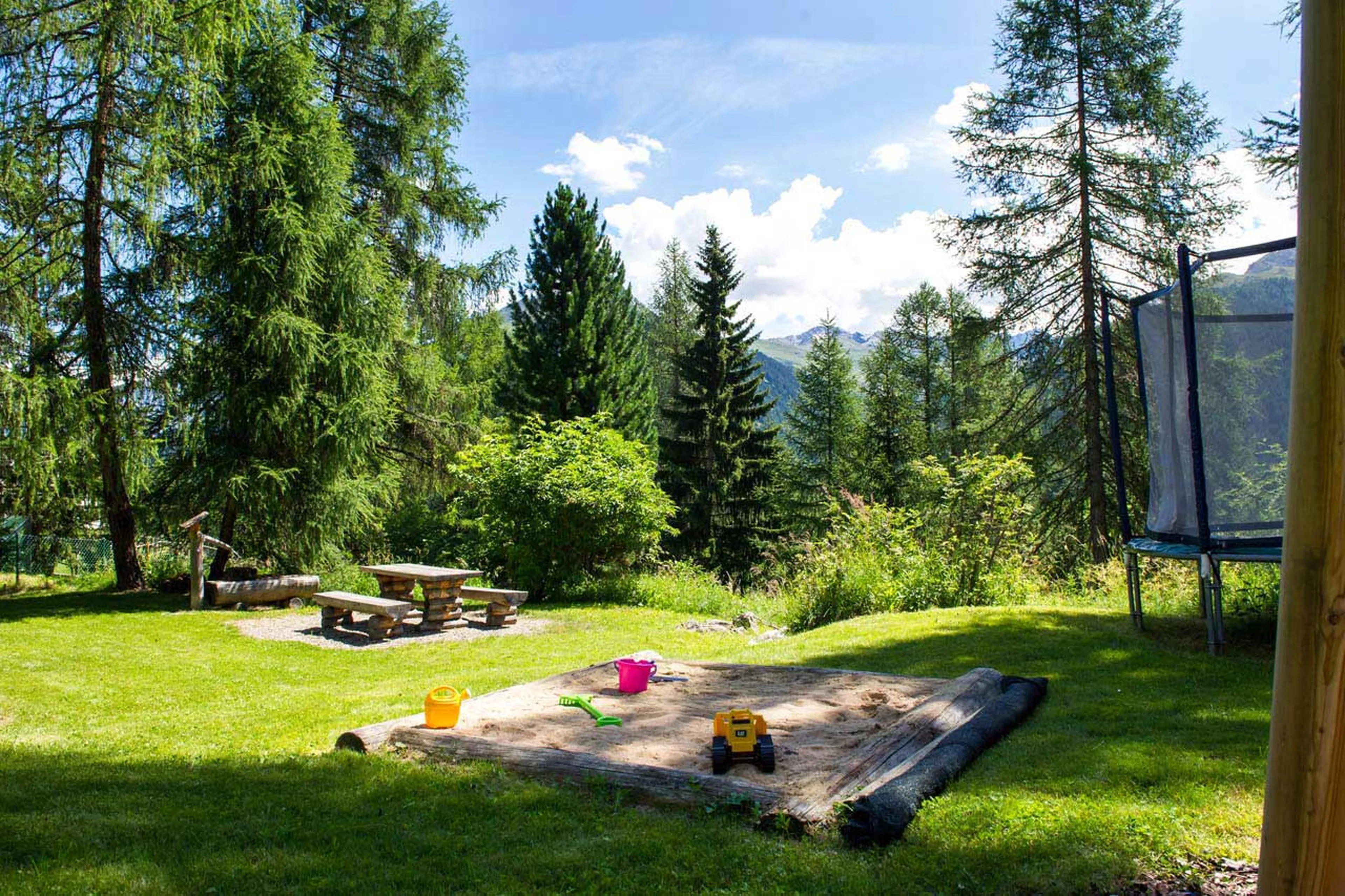 Sandpit and trampoline in garden at Tivoli Lodge in Davos