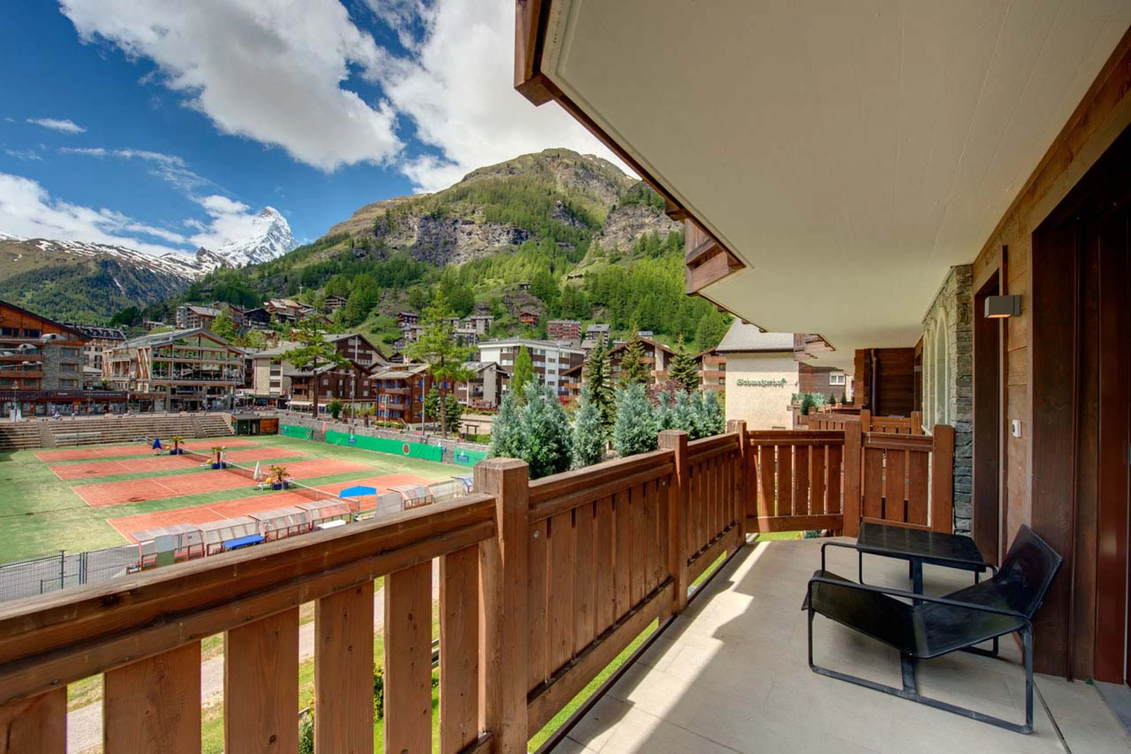 Balcony view overlooking tennis courts at Whymper Residence in Zermatt